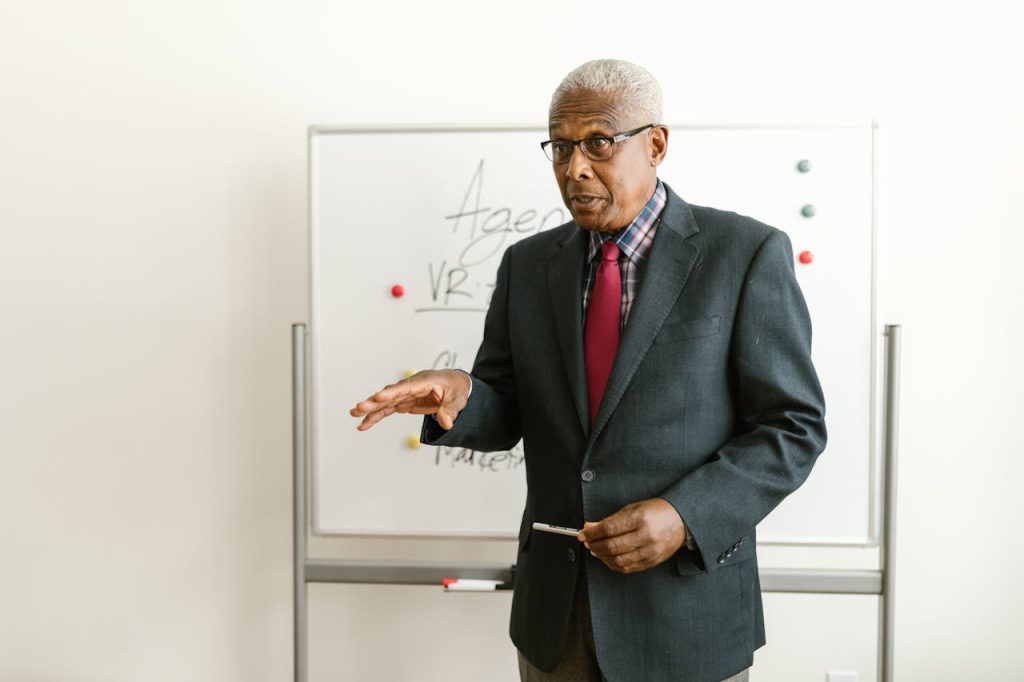 Elderly businessman presenting with a whiteboard in an office setting.